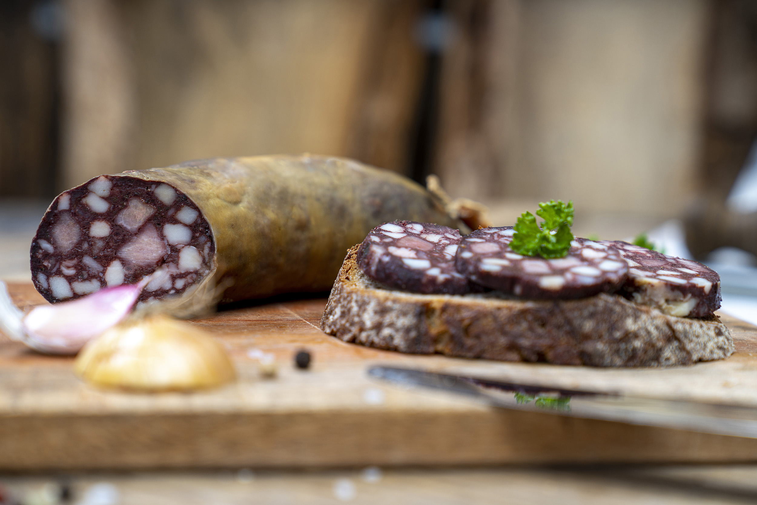 Hausmacher Rotwurst Eine Scheibe Brot mit Rotwurst Scheiben. Auf dem Brett Kräuter, Zwiebeln und die Wurst.